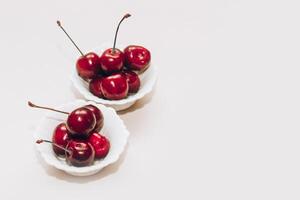 Ripe red cherries in white plates on the table. photo