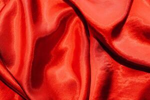 Red shiny texture of silk satin satin with folds. photo