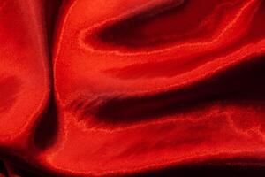 Red shiny texture of silk satin satin with folds. photo