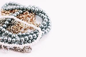 A necklace of gray beads with chain decorations on a white aesthetic background. photo