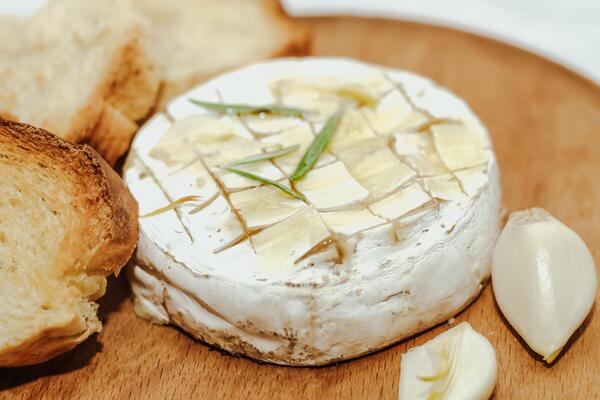 White baguette cut into pieces with olive oil and Camembert cheese on the table.