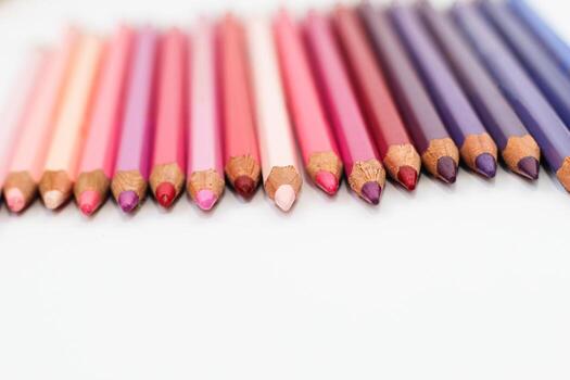 Multi-colored pencils lie on a white table, the violet range of colors photo