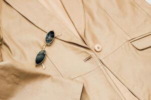 Gold-rimmed sunglasses on the texture of a brown leather jacket, genuine soft leather photo