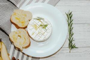 White baguette cut into pieces with olive oil and Camembert cheese on the table. photo