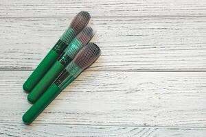 Green makeup brushes on a wooden table. photo