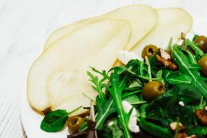 Salad with pears, herbs, arugula, prosciutto, cheese, green olives and nuts. photo