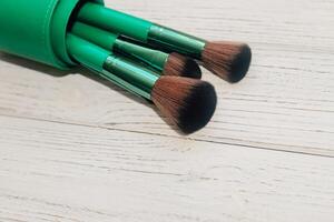 Green case with make-up bones on a wooden table. photo