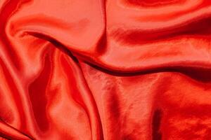 Red shiny texture of silk satin satin with folds. photo