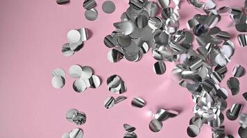 Silver tinsel confetti blow in Slow Motion on pink background. Christmas and New Year holiday design or birthday video