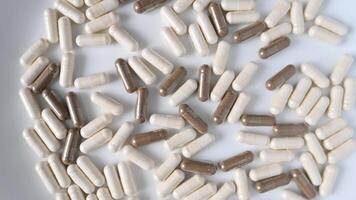 Close up of rotation soft white and gray medicine pills or capsules on white background video