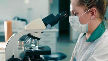 Scientist Researcher examines virus samples under a microscope. Female Research Scientist Looks at Biological Samples Under Microscope. video