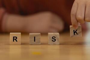 A person is holding wooden blocks and spelling out the word RISK. Concept of caution and awareness about to protect risk. photo