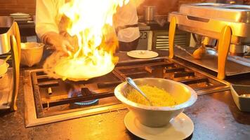 een chef bereidt zich voor pasta in een snel voedsel stijl. de frituren pan is Aan brand. olie dat vangsten brand gedurende Koken video