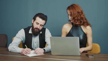 twee echt bedrijf mensen werken samen. de vrouw dicteert de informatie en de Mens schrijft het naar beneden Aan papier met een pen. communicatie tussen kantoor arbeiders. video