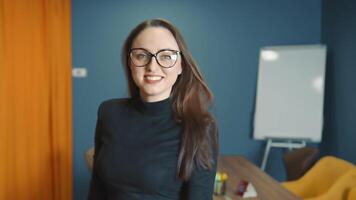 zuversichtlich und lächelnd Geschäft Frau im Brille von kaukasisch Aussehen Stehen im das Büro und suchen beim das Kamera. das aussehen von ein ziemlich glücklich Frau. Porträt von ein Büro Arbeiter. video