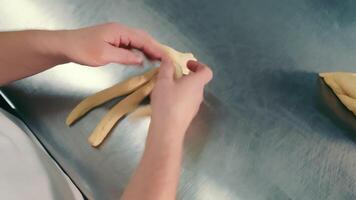 de bakker kneedt de deeg door hand- voor maken een gevlochten broodje. handgemaakt deeg. bakken brood video