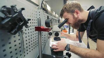 Diagnostics of diesel injectors under a microscope. The master examines the nozzle under a microscope to detect defects. video