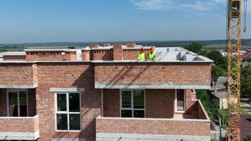 Antenne Aussicht ein Baumeister und ein Architekt auf das Dach von ein Backstein Haus prüfen das Konstruktion planen video