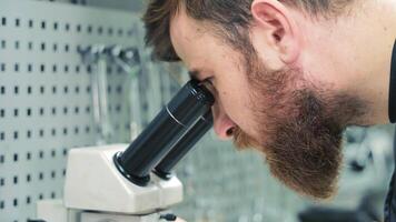 Diagnostics of diesel injectors under a microscope. The master examines the nozzle under a microscope to detect defects. video