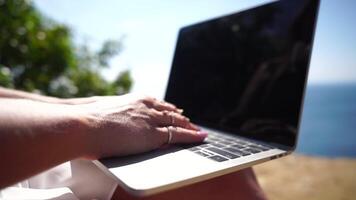 Woman laptop sea. Working remotely on seashore. Happy successful woman female freelancer working on laptop by the sea at sunset, makes a business transaction online. Freelance, remote work on vacation video