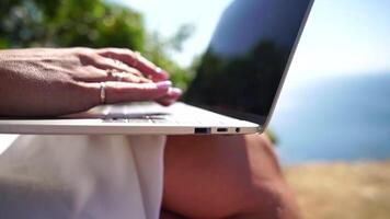 Woman laptop sea. Working remotely on seashore. Happy successful woman female freelancer working on laptop by the sea at sunset, makes a business transaction online. Freelance, remote work on vacation video