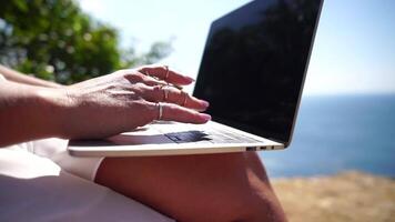 Woman laptop sea. Working remotely on seashore. Happy successful woman female freelancer working on laptop by the sea at sunset, makes a business transaction online. Freelance, remote work on vacation video