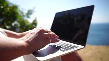 Woman laptop sea. Working remotely on seashore. Happy successful woman female freelancer working on laptop by the sea at sunset, makes a business transaction online. Freelance, remote work on vacation video