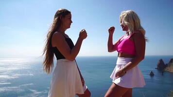 Rock paper scissors being played by two young woman. Close up view female hands playing stone, scissors and paper on sea background, funny carefree game. Friendship, dealing with conflict, having fun. video