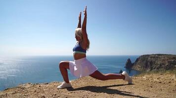 vrouw zee geschiktheid. gelukkig blond vrouw, geschiktheid instructeur in sportkleding aan het doen uitrekken en pilates Aan klif over- de zee. vrouw geschiktheid yoga routine- concept. gezond levensstijl. video