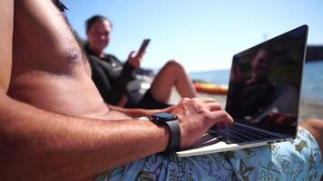 Man laptop sea. Working remotely on seashore. Happy successful man, male freelancer working on laptop on beach, relieves stress from work to restore life balance. Freelance, remote work on vacation video