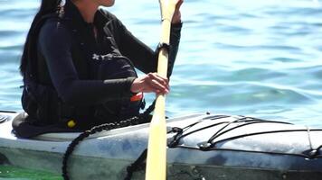 mulher mar caiaque. feliz sorridente mulher dentro caiaque em oceano, remar com de madeira remo. calma mar água e horizonte dentro fundo. ativo estilo de vida às mar. verão período de férias. video