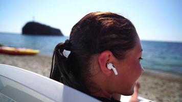 Woman with smartphone. Close-up of woman's hands holding vertical mobile phone and swiping up finger application page against background of sea and beach video