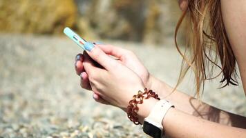 mujer con teléfono inteligente de cerca de mujer manos participación vertical móvil teléfono y deslizar arriba dedo solicitud página en contra antecedentes de mar y playa video