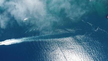 Aerial boat race. Luxury cruise trip on blue sea with foggy clouds at sunny day. Fast boat with white footprints on water surface. Seascape from drone. Holiday, vacation and travel. video