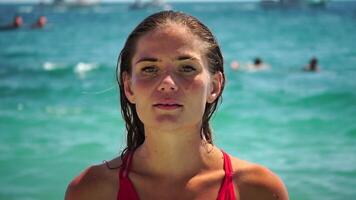 jovem mulher com grandes cabelo dentro uma vermelho roupa de banho e pulseiras dentro boho estilo desfrutando a ondas em a de praia dentro verão. adorável feliz feminino relaxante às verão de praia tendo período de férias. lento movimento. video