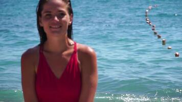 Woman travel sea. Happy woman with long hair in a red swimsuit and bracelets in boho style enjoying the waves on the beach in summer. Adorable happy feminine relaxing at summer beach on vacation. video