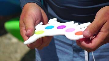 man playing pop it fidget toys, closeup on hands. unrecognizable male pushes bubbles on colorful silicone poppit with fingers. close up on multicolor anti-stress toys. stress reliever video