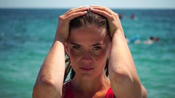 jovem mulher com grandes cabelo dentro uma vermelho roupa de banho e pulseiras dentro boho estilo desfrutando a ondas em a de praia dentro verão. adorável feliz feminino relaxante às verão de praia tendo período de férias. lento movimento. video