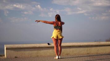 femme été danse. silhouette de une content femme qui danses, tourne et soulève sa mains à le ciel. une espiègle Jeune femme jouit sa content moment dansant dans le des rayons de le d'or Soleil. video