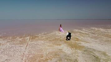 Woman in flying dress on pink salt lake. Salt production facilities saline evaporation pond fields in the salty lake. video