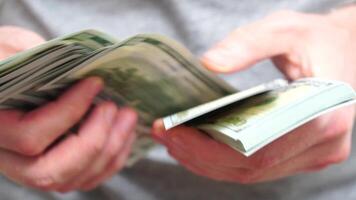 Male hands counting a stack of hundred-dollar US banknotes. Concept of investment, money exchange, financial transactions or business negotiations. Selective focus. Close-up. Slow motion video