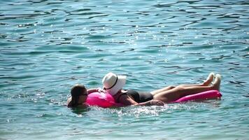 été vacances femme flotteurs sur un gonflable Donut matelas, une l'eau jouet nager anneau. méconnaissable Jeune femme relaxant et profiter famille été Voyage vacances vacances sur le mer. lent mouvement video