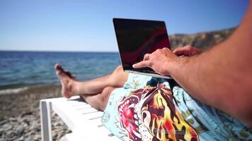 homem computador portátil mar. trabalhando remotamente em Beira Mar. feliz bem sucedido homem, masculino trabalhador autonomo trabalhando em computador portátil em praia, alivia estresse a partir de trabalhos para restaurar vida equilíbrio. freelance, controlo remoto trabalhos em período de férias video