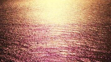 Sea water surface. Aerial view on golden sea water at sunset. Sun glare. Abstract nautical summer ocean nature. Holiday, vacation and travel concept. Nobody. Slow motion. Weather and climate change video