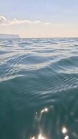 Sea water surface. Low angle view from kayak, camera flies over clear calm sea water. Nobody. Holiday recreation concept. Abstract nautical summer ocean nature. Slow motion. Close up. Vertical video