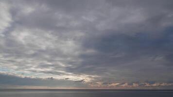 zonsondergang lucht wolken tijdsverloop. rood brandend zonsondergang over- zee en gouden schijnend water oppervlakte met bokeh lichten van zon. abstract natuur zomer oceaan zee achtergrond. weer en klimaat verandering video