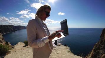 Digital nomad, Business woman working on laptop by the sea. Pretty lady typing on computer by the sea at sunset, makes a business transaction online from a distance. Freelance, remote work on vacation video