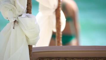 bangalôs mar. de praia salão cama com branco sedoso cortinas. salão cama com marquise às à beira-mar. de praia cadeiras e guarda-sóis. verão período de férias recorrer conceito. video