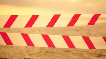 rood wit waarschuwing plakband barrière lint swinging in de wind aan de overkant exotisch zee strand achtergrond zonder mensen. Nee binnenkomst rood wit voorzichtigheid plakband. Nee vakantie concept, vertraagd reis, Nee zomer plannen video