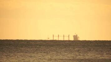 miraggio di carico nave nel il mare al di là il orizzonte. nave andare in barca nel il mare. piccolo onde su il d'oro superficie di caldo acqua con bokeh luci a partire dal il sole. mare, natura e all'aperto viaggio. video